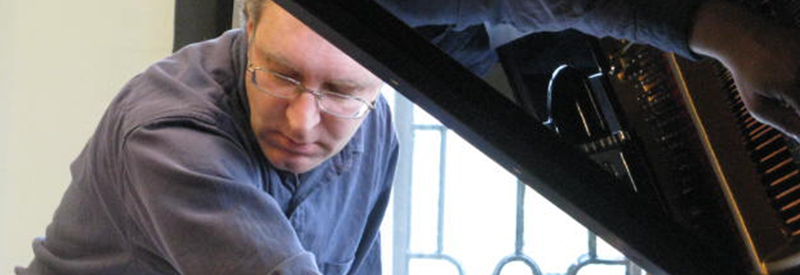 Anthony Clare photographed looking over a piano