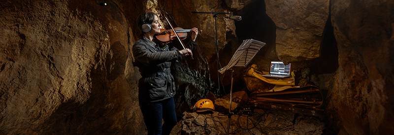 Amanda Johnson playing violin in cave