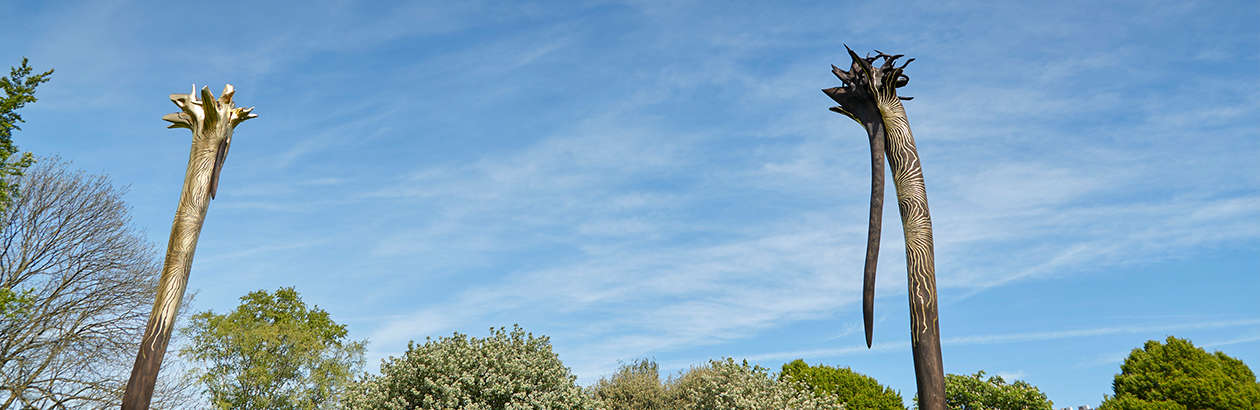 Two inverted trees guilded in ondulating pattern with the blue sky in the background