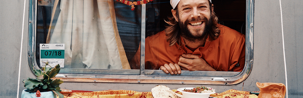 Man poking head out of food van with food in front