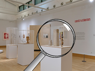 A gallery space with minimalist sculptures with a magnifying glass