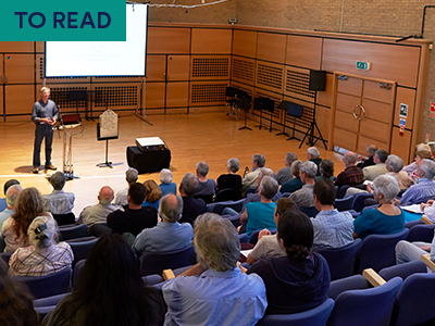 A photo of an auditorium listening to a speaker