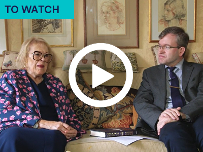 Dr Nigel Astor on right interviewing Lady Antonia Fraser who sits on the left . Both seated on a sofa with cushions above and framed paintings on wall behind. Keyword in the corner TO WATCH