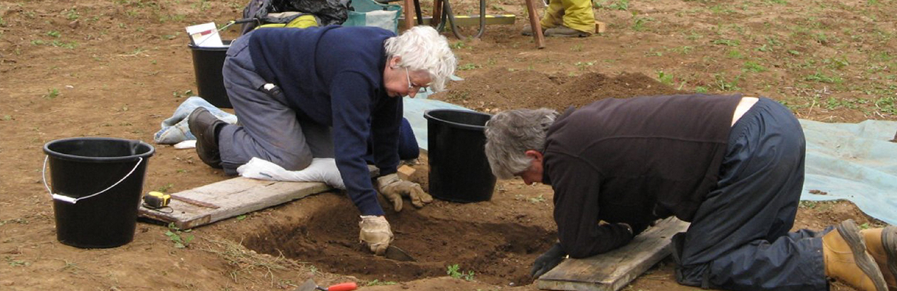 Photograph of man and woman bending over ditch conducting archaeological digging