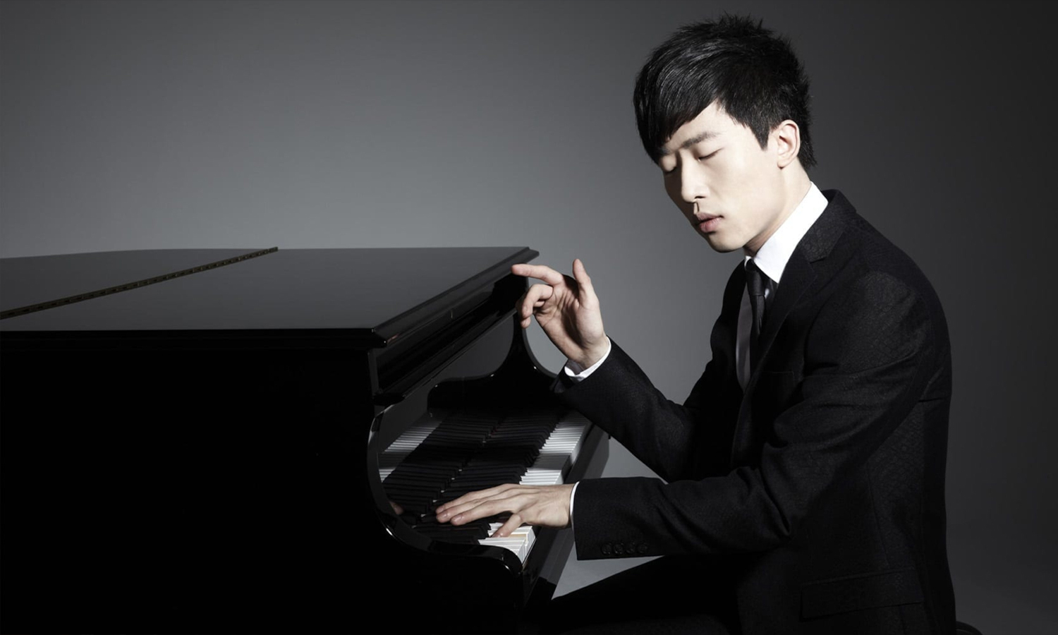 Ji Liu performing at the piano with a grey background