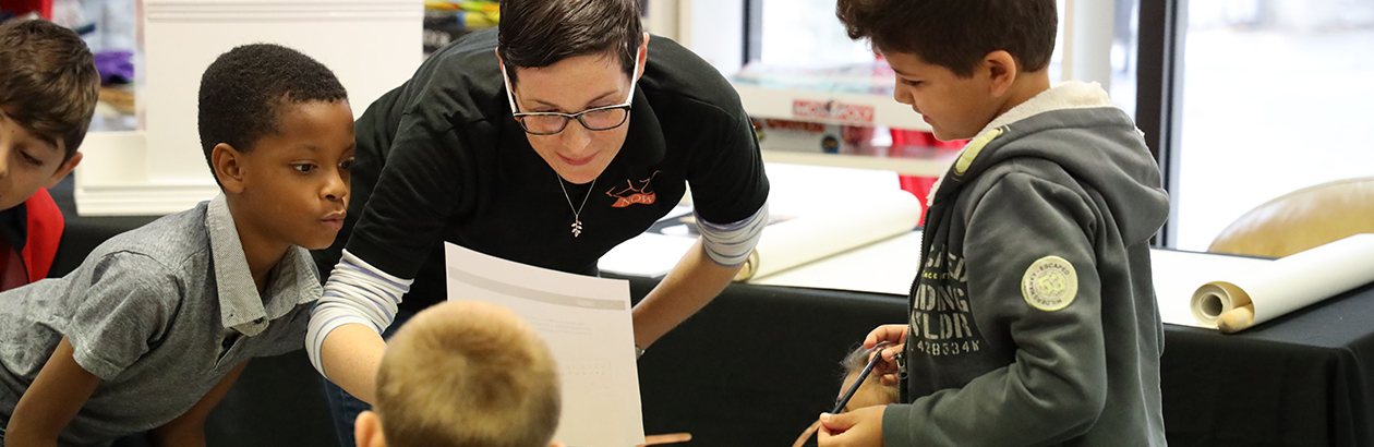 Photograph of adult bent to teach four children 