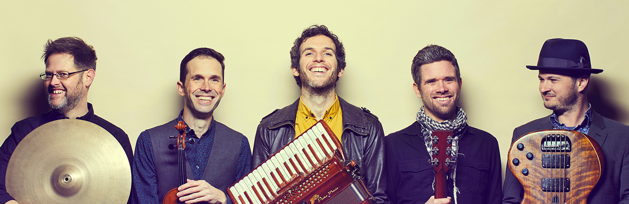 Photograph of band MABON standing on set with screen backdrop