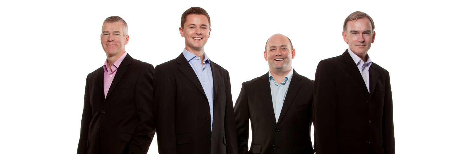 Four men in black suits on a white background