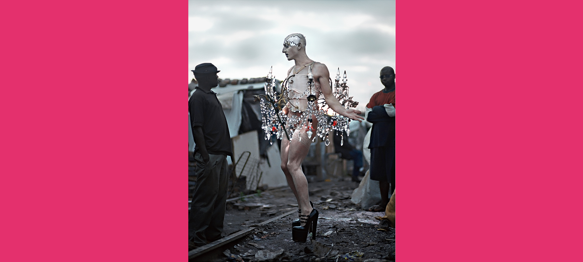 a photo of a man in high heels and a chandelier hung around his body in a dark and poor townark 