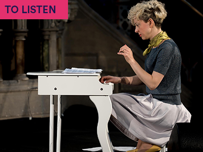 Photograph of Xenia Pestova Bennett playing miniature piano with grey top and green scarf. Keywords in corner: TO LISTEN